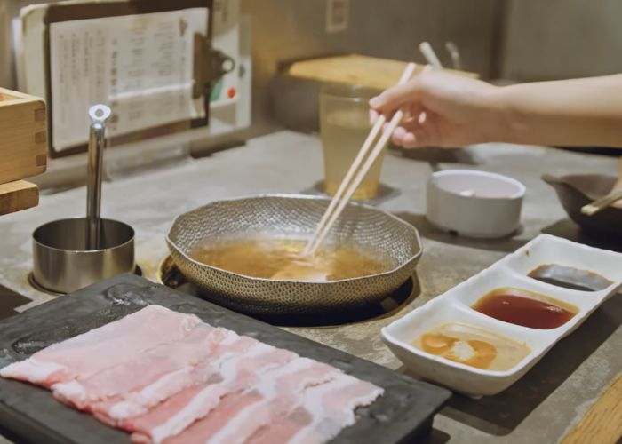 Shizuka dunking slices of meat in a boiling broth at Shabu Shabu Retasu.